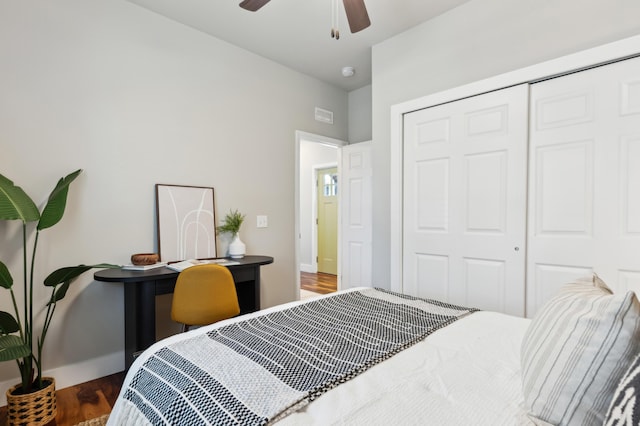 bedroom with a ceiling fan, visible vents, wood finished floors, baseboards, and a closet