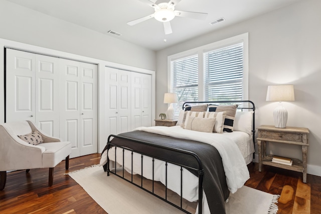 bedroom featuring ceiling fan, visible vents, two closets, and wood finished floors