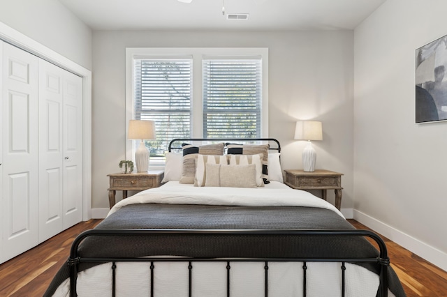 bedroom with wood finished floors, visible vents, a closet, and baseboards