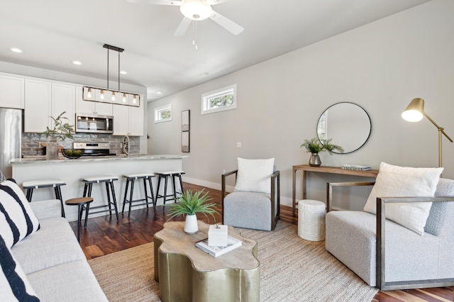 living area featuring recessed lighting, ceiling fan, baseboards, and wood finished floors