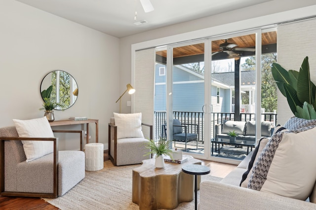 living room featuring wood finished floors, a ceiling fan, and visible vents