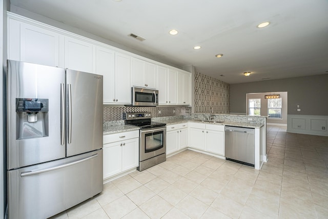 kitchen featuring visible vents, white cabinets, appliances with stainless steel finishes, open floor plan, and light stone countertops