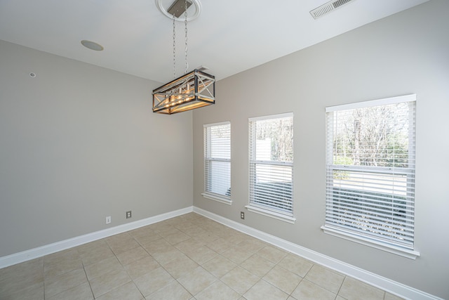 empty room with light tile patterned floors, visible vents, and baseboards