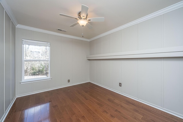 spare room with visible vents, dark wood-style floors, ceiling fan, ornamental molding, and a decorative wall