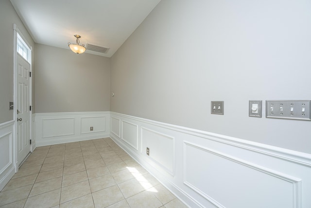 unfurnished dining area with light tile patterned floors, wainscoting, and visible vents