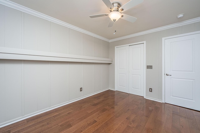 unfurnished bedroom with a closet, ornamental molding, a decorative wall, and dark wood-type flooring