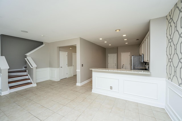 kitchen with light tile patterned floors, recessed lighting, a peninsula, white cabinets, and freestanding refrigerator