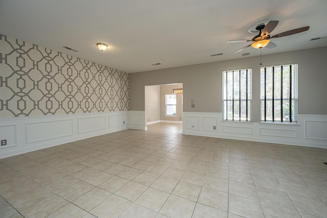 spare room featuring wallpapered walls, wainscoting, visible vents, and light tile patterned flooring