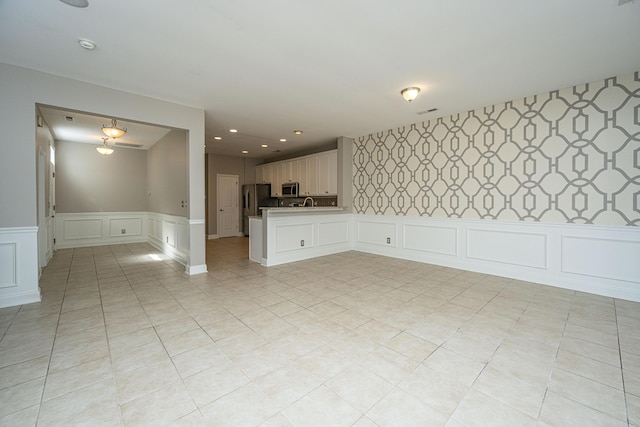 unfurnished room featuring a decorative wall, recessed lighting, visible vents, wainscoting, and wallpapered walls