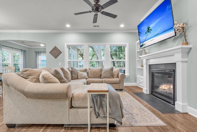 3873 Hanoverian Dr, Mount Pleasant, SC 29429 - living area featuring crown molding, ceiling fan, wood finished floors, a fireplace with flush hearth, and arched walkways