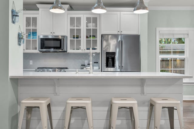 3873 Hanoverian Dr, Mount Pleasant, SC 29429 - kitchen featuring stainless steel appliances, white cabinetry, decorative backsplash, a breakfast bar, and ornamental molding