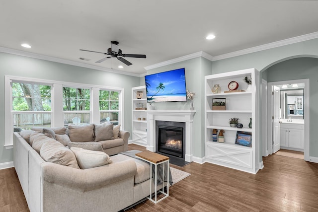 3873 Hanoverian Dr, Mount Pleasant, SC 29429 - living area with arched walkways, a fireplace with flush hearth, ceiling fan, dark wood-style flooring, and ornamental molding