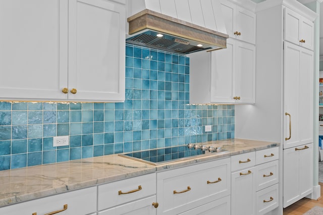 kitchen featuring black electric stovetop, white cabinets, light stone countertops, tasteful backsplash, and custom range hood