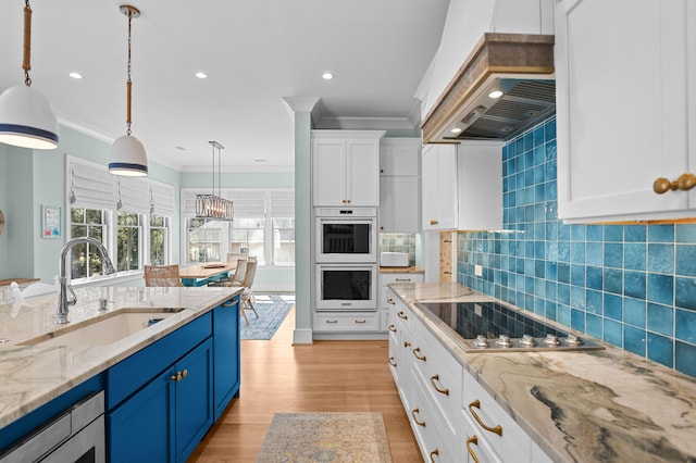 kitchen featuring white double oven, black electric cooktop, premium range hood, a sink, and blue cabinetry