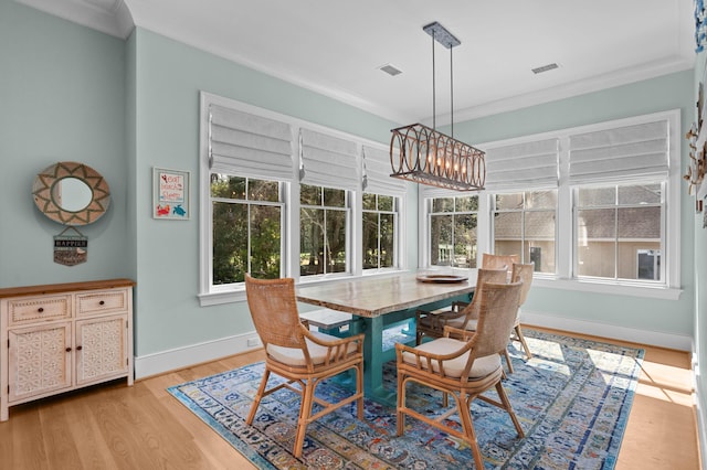 dining space featuring baseboards, light wood-type flooring, visible vents, and crown molding