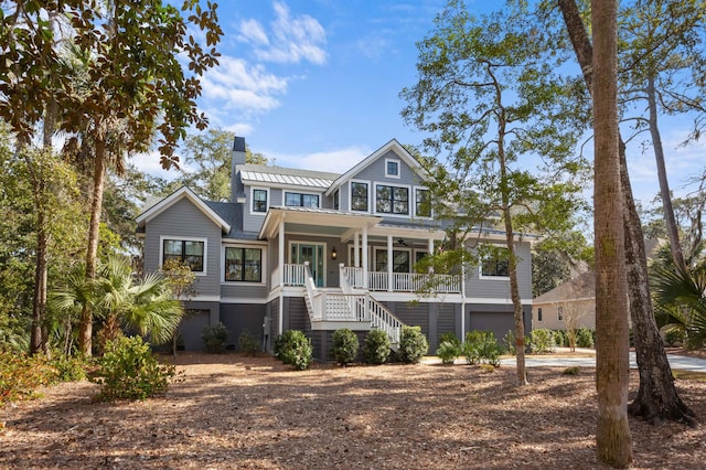 view of front facade with a chimney, a porch, an attached garage, ceiling fan, and stairs