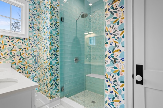 bathroom featuring double vanity, a stall shower, a sink, and wallpapered walls