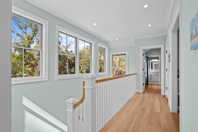 corridor featuring light wood finished floors, recessed lighting, plenty of natural light, and an upstairs landing