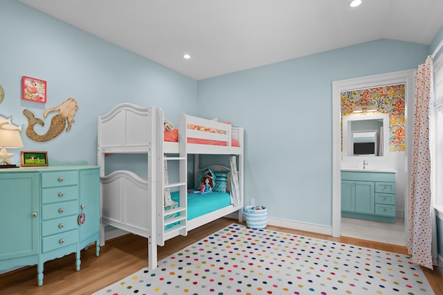 bedroom featuring lofted ceiling, recessed lighting, a sink, ensuite bath, and wood finished floors