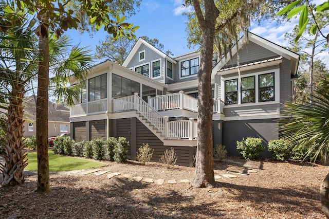 back of property with a sunroom and stairs