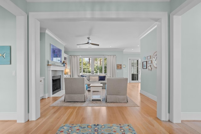 dining room with a fireplace with flush hearth, baseboards, wood finished floors, and crown molding