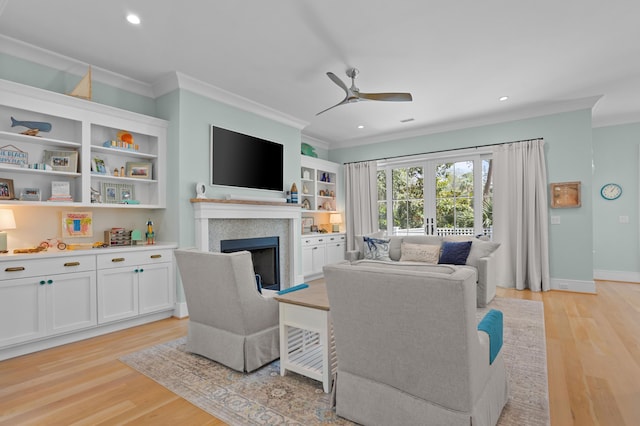 living area with ceiling fan, light wood finished floors, a fireplace, and crown molding