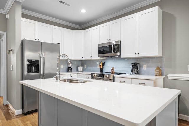 81 Sandbar Ln Unit 23, Folly Beach, SC 29439 - kitchen featuring appliances with stainless steel finishes, light wood-type flooring, decorative backsplash, light countertops, and ornamental molding