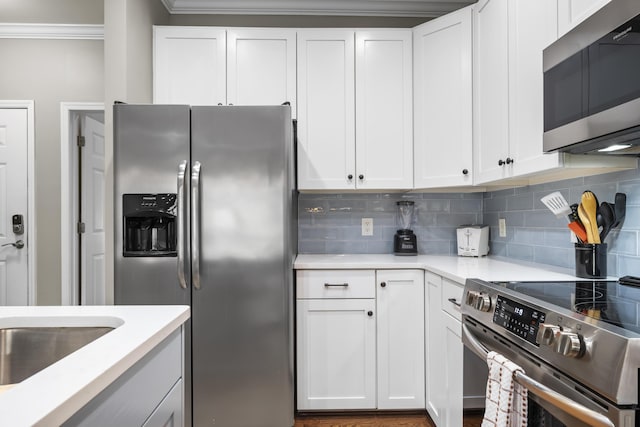 81 Sandbar Ln Unit 23, Folly Beach, SC 29439 - kitchen with appliances with stainless steel finishes, crown molding, backsplash, light countertops, and white cabinetry