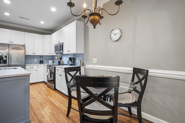 81 Sandbar Ln Unit 23, Folly Beach, SC 29439 - kitchen featuring appliances with stainless steel finishes, light countertops, decorative backsplash, white cabinetry, and light wood-style flooring