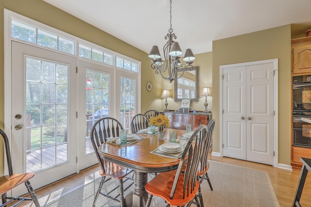 dining area featuring light wood-type flooring, a notable chandelier, and plenty of natural light