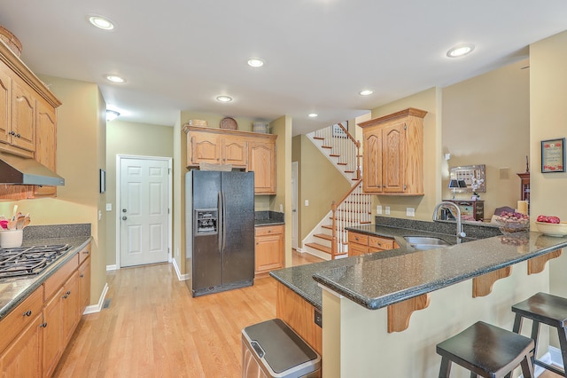 kitchen with light hardwood / wood-style floors, sink, kitchen peninsula, and black fridge