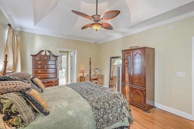 bedroom featuring light hardwood / wood-style floors, ornamental molding, a raised ceiling, and ceiling fan