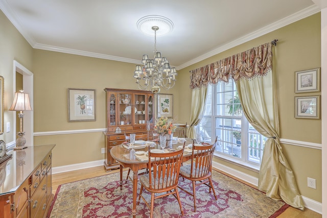 dining space featuring crown molding, a notable chandelier, and light hardwood / wood-style flooring