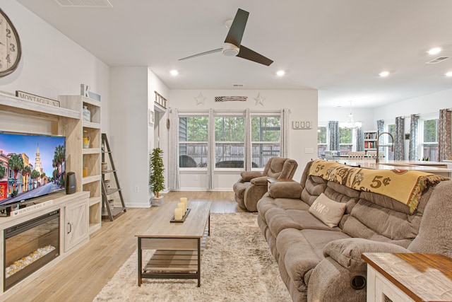 living room featuring a ceiling fan, recessed lighting, a chandelier, and light wood-style flooring