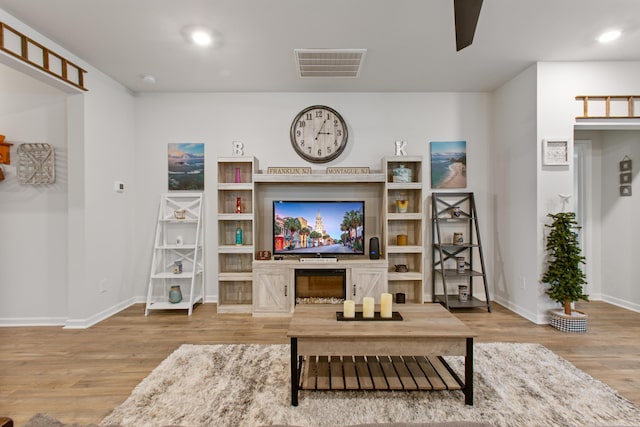 living area with light wood-type flooring, baseboards, a ceiling fan, and recessed lighting