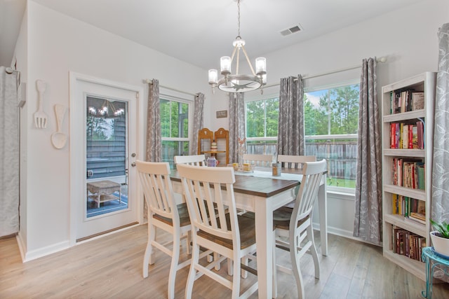 dining room with a chandelier, light wood-style flooring, and baseboards