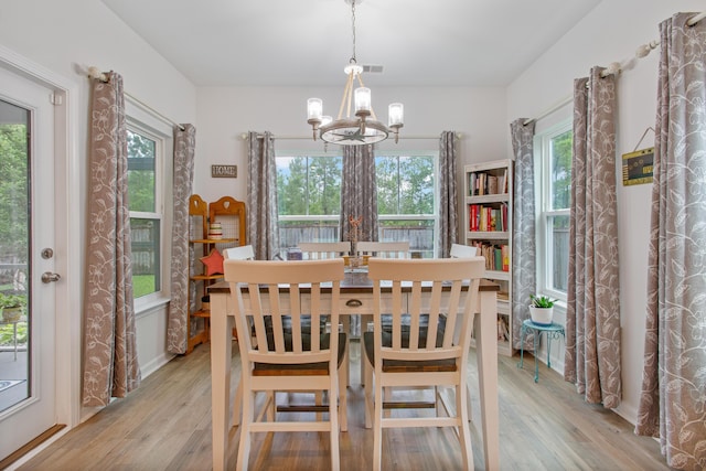 dining room featuring a chandelier, light wood finished floors, and healthy amount of natural light
