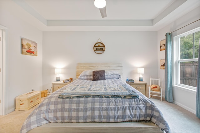 bedroom featuring carpet flooring, baseboards, a raised ceiling, and a ceiling fan
