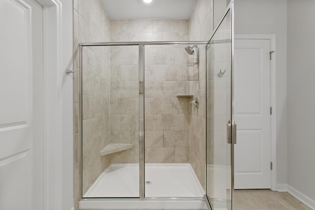 full bath with a stall shower, tile patterned floors, and baseboards