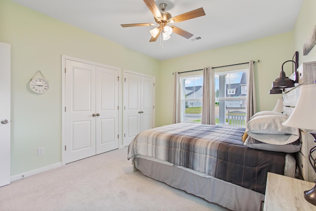 bedroom featuring two closets, carpet flooring, baseboards, and a ceiling fan