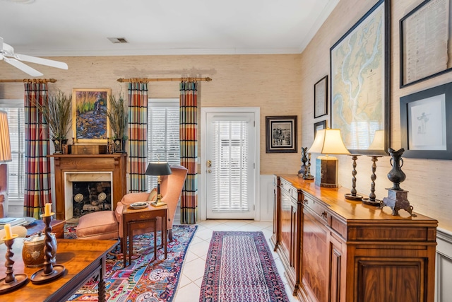 sitting room featuring ceiling fan, light tile patterned flooring, crown molding, and a high end fireplace