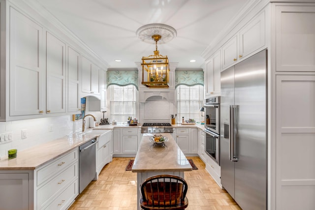 kitchen featuring appliances with stainless steel finishes, light parquet flooring, decorative light fixtures, and sink