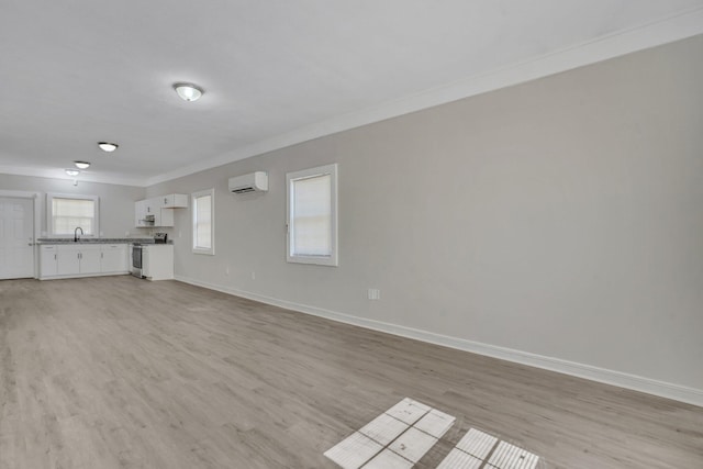 unfurnished living room featuring ornamental molding, a wall mounted air conditioner, and light hardwood / wood-style flooring