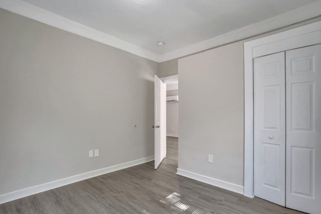 unfurnished bedroom featuring ornamental molding, a closet, and hardwood / wood-style floors