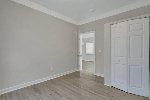 unfurnished bedroom with a closet, crown molding, and light wood-type flooring