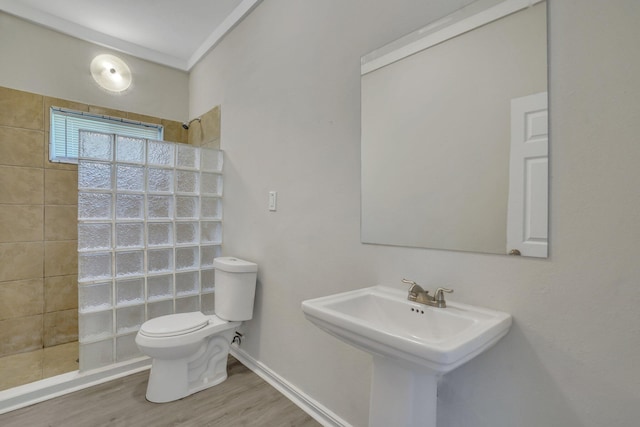 bathroom with a tile shower, hardwood / wood-style flooring, sink, and toilet