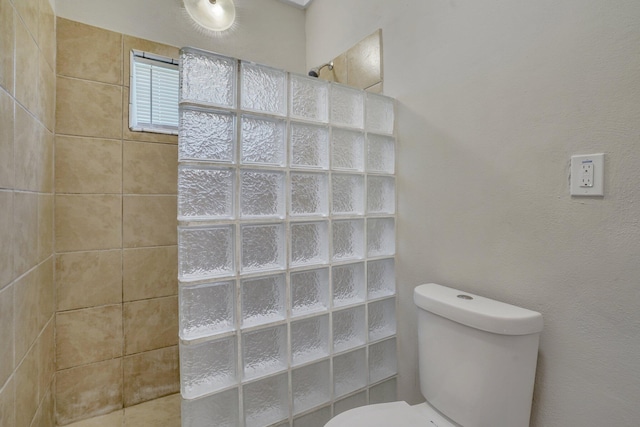 bathroom with tiled shower and toilet