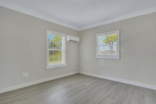 spare room with ornamental molding, a wall mounted AC, and light hardwood / wood-style flooring