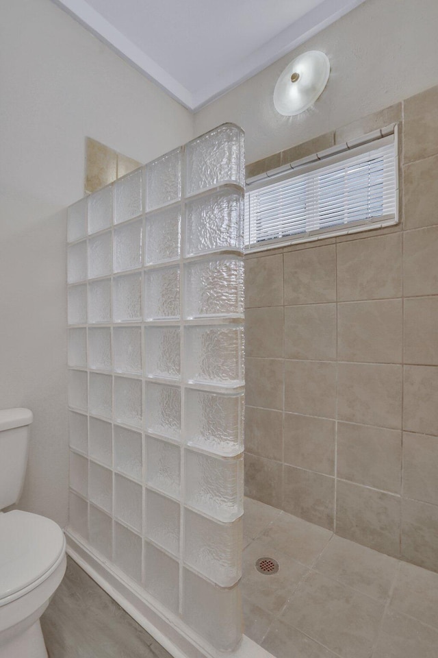 bathroom featuring a tile shower and toilet