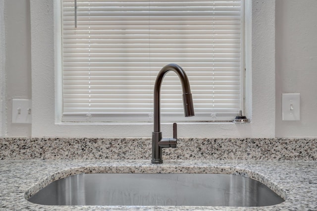 details featuring light stone countertops and sink